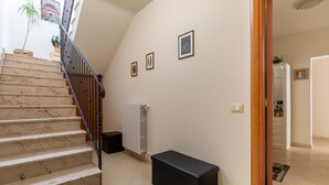Una escalera con acabado de mármol, un banco negro y un radiador en la pared.