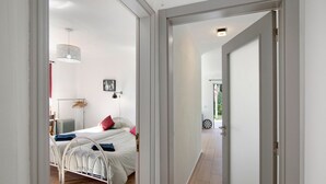 A bedroom with a bed, bedside table, lamp, and a view through an open door. - Vacation Home "Arcadia T3" with Private Pool, 2 Terraces & Wi-Fi (São Bartolomeu de Messines)