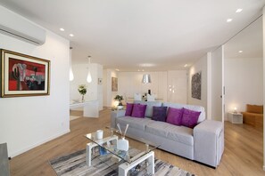 A modern living room with a glass coffee table, a grey sofa with purple cushions, and a white couch. - Apartment "Mare Nostrum" with Sea View, Shared Pool and Wi-Fi (Olhão)