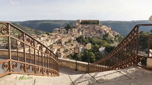 Una escalera con barandillas de metal decoradas que lleva a una vista de un pueblo histórico con edificios en una ladera.
