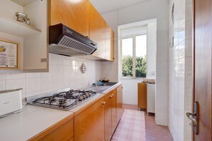 A kitchen with wooden cabinets, a gas stove, a window, and a tiled backsplash.