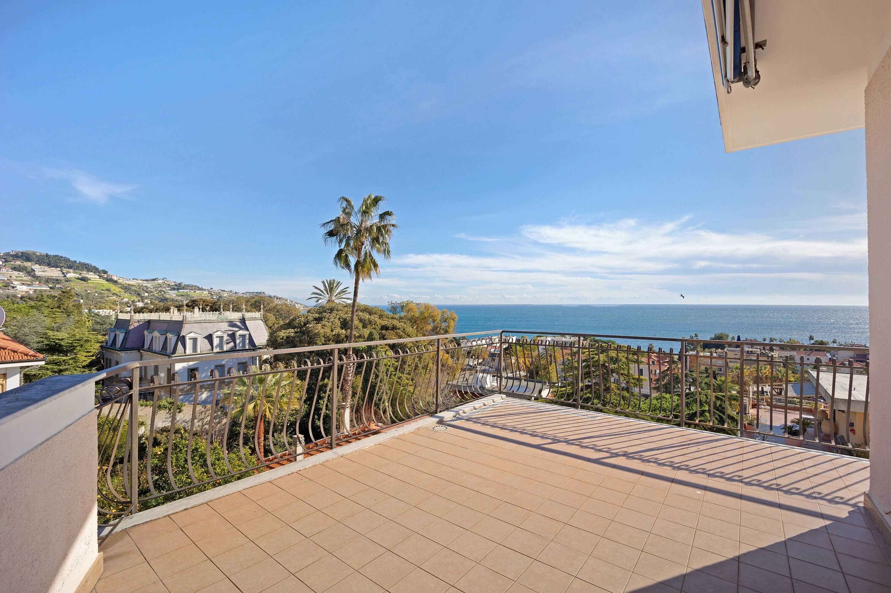 A balcony with a view of the sea and surrounding buildings.