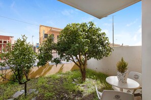 Un balcon avec un petit arbre, une plante en pot et une table avec des chaises.