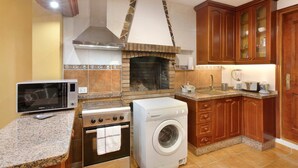Een keuken met een inbouwoven, magnetron, wasmachine en een stenen openhaard.