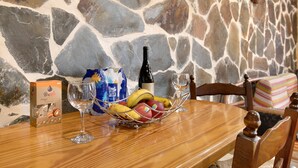 Een eettafel met een schaal fruit, een wijnfles en glazen.