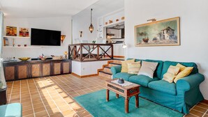 A living room with a sofa, a coffee table, a TV, and a staircase leading to an upper level. - Vacation Home "Los Angeles" with Sea View, Private Terrace & Wi-Fi (Tías)