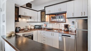 A modern kitchen with stainless steel appliances, white cabinetry, and a dark countertop. - Vacation Home "Los Angeles" with Sea View, Private Terrace & Wi-Fi (Tías)