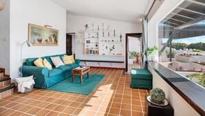 A living room with a teal sofa, a coffee table, and a bookshelf. - Vacation Home "Los Angeles" with Sea View, Private Terrace & Wi-Fi (Tías)