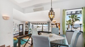 A dining area with a glass table, chairs, and a hanging lantern. - Vacation Home "Los Angeles" with Sea View, Private Terrace & Wi-Fi (Tías)