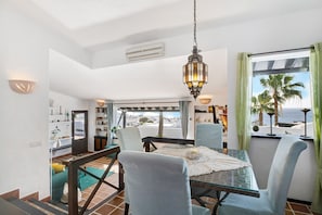 A dining area with a glass table, chairs, and a hanging lantern.
