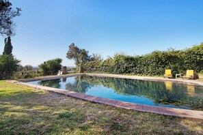 A rectangular swimming pool with a brick border, surrounded by grass and trees, with two yellow lounge chairs on the right side. - Vacation Home "Arcadia T2" with Private Pool, 2 Terraces & Wi-Fi (São Bartolomeu de Messines)