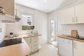 A modern kitchen with a dishwasher, a window, and a view of the outside.