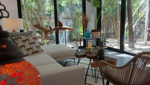 A modern living room with a white sofa, a wicker chair, a small table with candles, and a decorative shark sculpture. - Increíble Townhouse con piscina privada (Tulum)