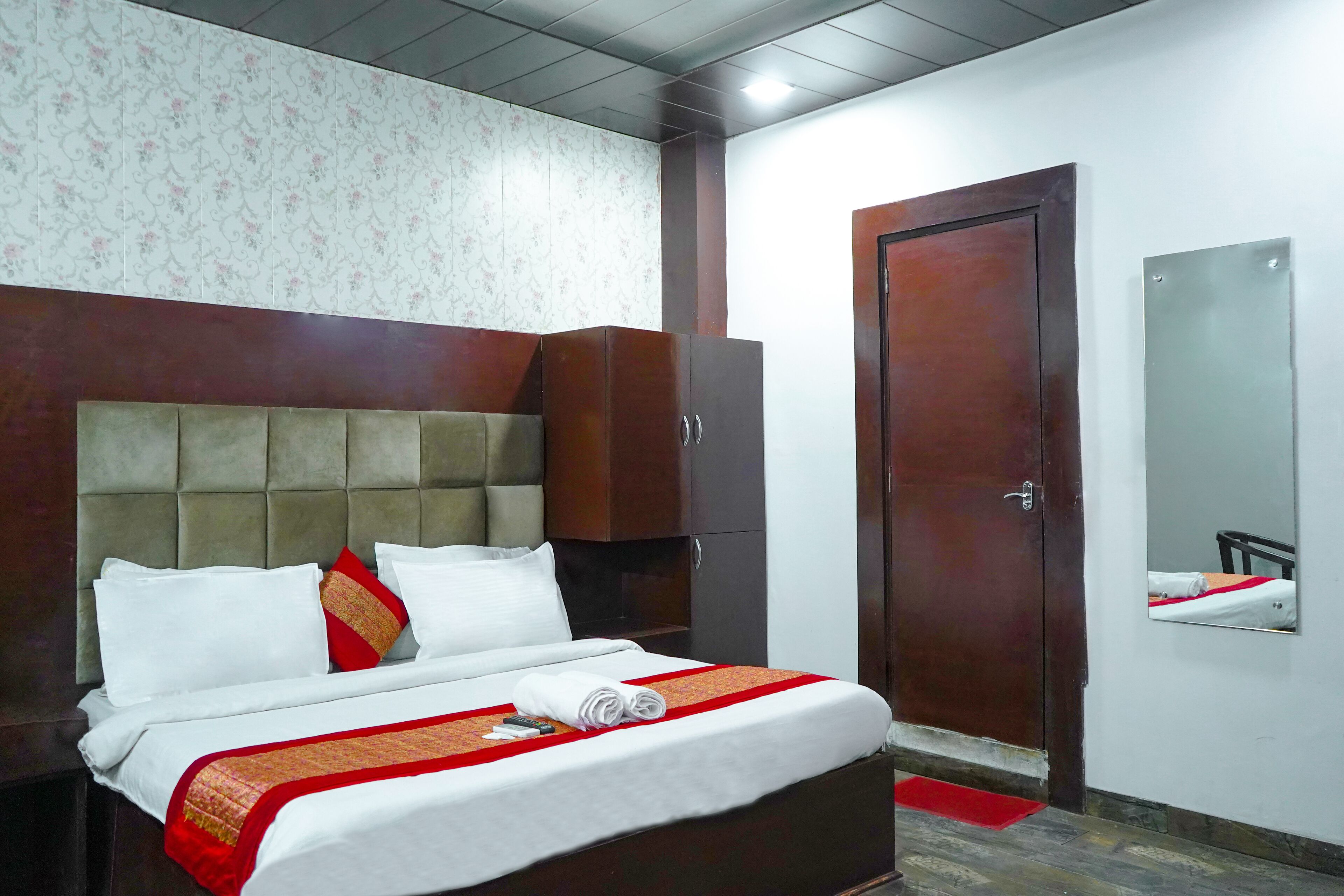 Habitación de hotel con una cama grande, un armario, una puerta y un espejo en la pared.