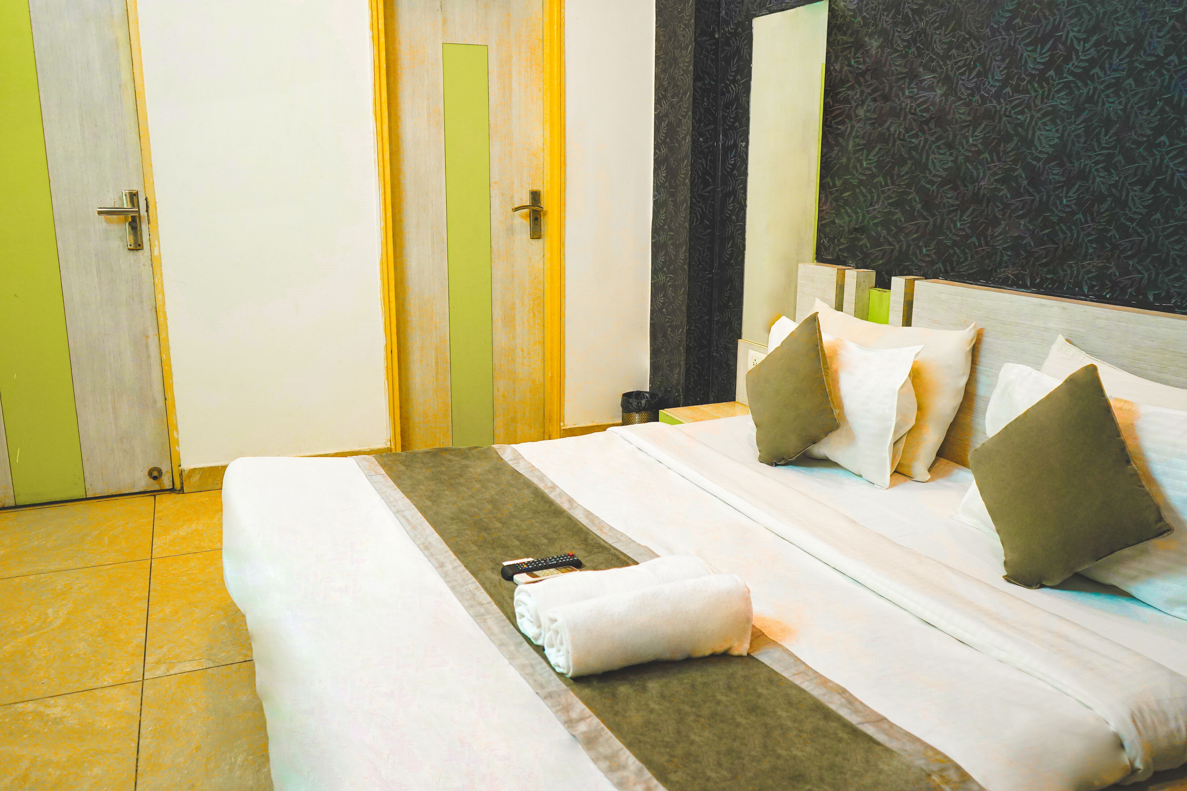 A hotel room with a neatly made bed, a remote control, and a towel on the bed.