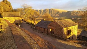 A rural village with stone buildings, a dirt road, and a mountainous backdrop. - Windsor Farm House , Stunning views/hot tub close to Scafell and Wastwater Lake (Wasdale)
