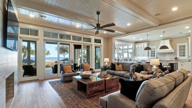 A spacious living room with a large sofa, coffee table, and a view of the beach through the sliding glass doors. - New Oceanfront Oasis in Palmetto Dunes with a private pool and EV plug (Hilton Head Island)