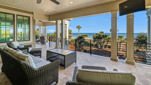 A covered outdoor area with wicker furniture, a ceiling fan, and a view of the ocean. - New Oceanfront Oasis in Palmetto Dunes with a private pool and EV plug (Hilton Head Island)