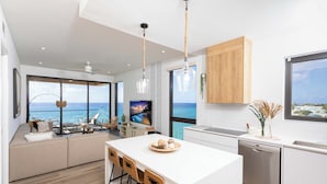 Una cocina moderna con una isla grande, armarios de madera y vista al océano.