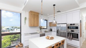 Una cocina moderna con armarios blancos, electrodomésticos de acero inoxidable y una isla grande con taburetes de bar.