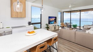 A modern kitchen with a large island, wooden cabinets, and a view of the sea. - SeaDreams 5: Oceanfront Condos w/Pool, Hot Tub, & Rooftop Patio (West Bay)