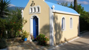 Una pequeña iglesia con puerta azul y cruz en la parte superior.