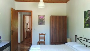 Un dormitorio con una cama, un armario de madera, una silla, un escritorio y un cuadro en la pared.
