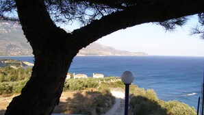 Un balcón con vista al mar, un farol y un árbol.