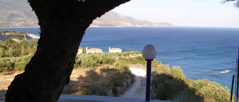 A balcony with a view of the sea, a lamp post, and a tree.