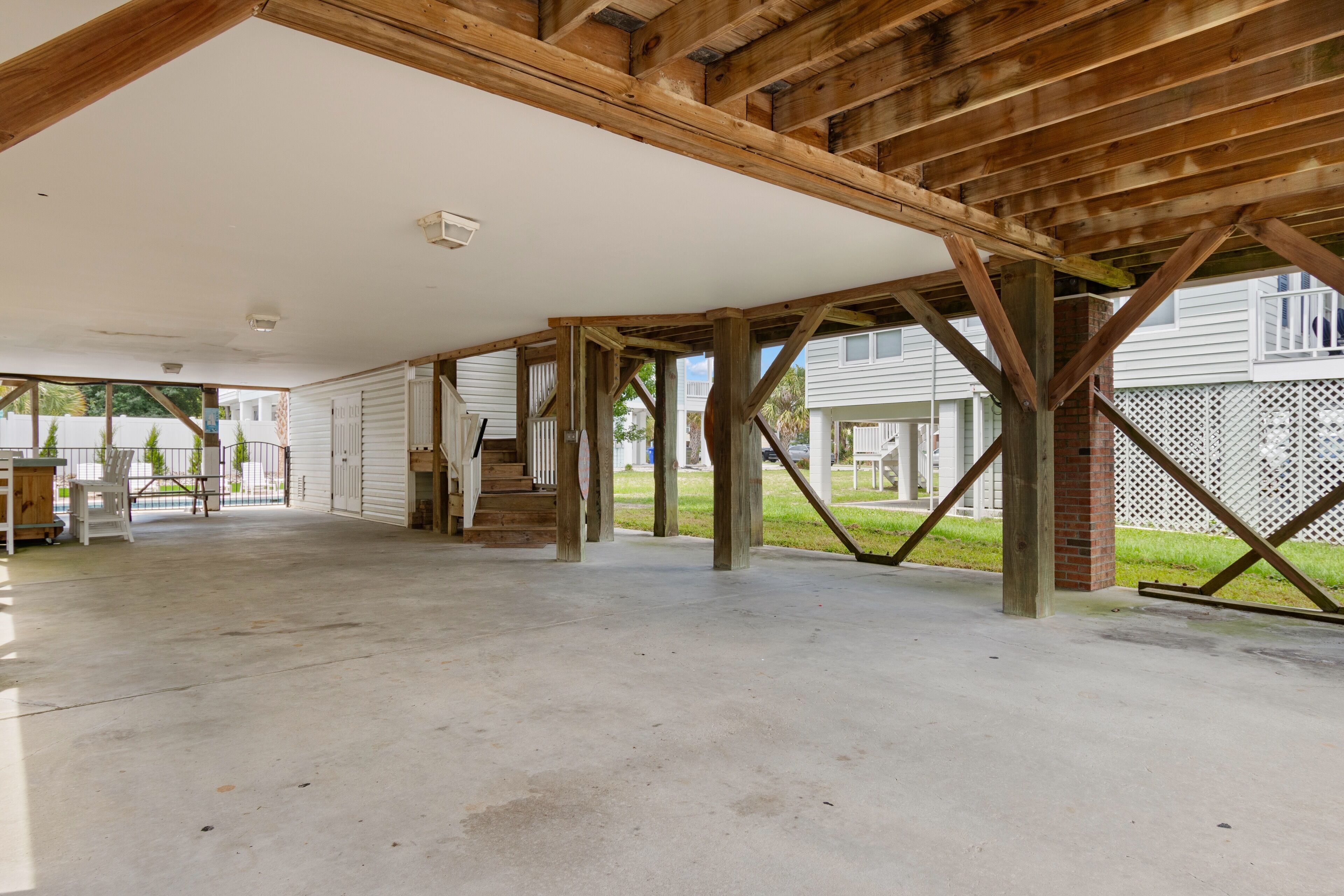 An open garage with a concrete floor and wooden beams supporting the ceiling.