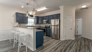 Una cucina moderna con mobili scuri blu, elettrodomestici in acciaio inossidabile e un'isola centrale con sgabelli da bar.