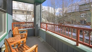 A balcony with wooden chairs and a table, overlooking a snowy landscape with buildings. - Silver Mill 8167-1br-walk To Slopes! Kids Ski Free! 1 Bedroom Condo by RedAwning (Keystone)