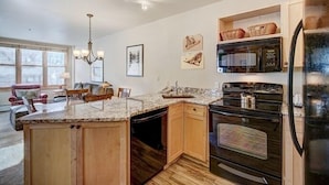 A kitchen with a central island, wooden cabinets, a built-in oven, and a microwave. - Silver Mill 8167-1br-walk To Slopes! Kids Ski Free! 1 Bedroom Condo by RedAwning (Keystone)