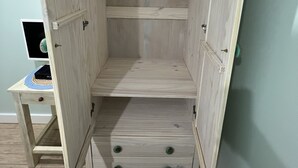 Un armadio in legno con due cassetti e uno scaffale, in una stanza con una scrivania e un computer.
