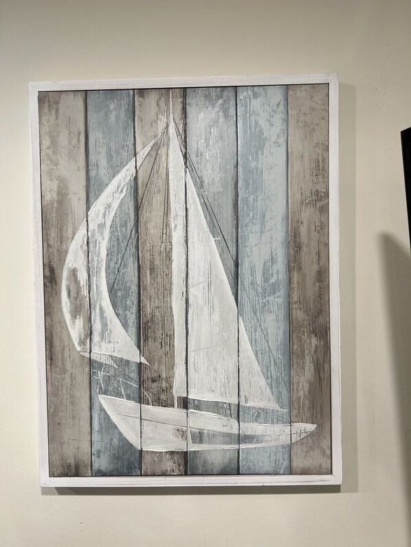 A wall-mounted artwork depicting a sailboat on a wooden background. - Steps to the Beach! (Manasquan)
