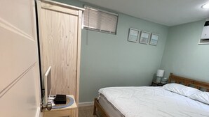 Una camera da letto con un letto in legno, un comodino con una lampada, un armadio e una finestra con tende.