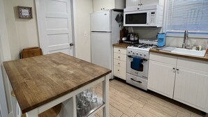 Una cucina compatta con mobili bianchi, un tavolo in legno e un forno a incasso.