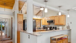 A modern kitchen with wooden cabinets, granite countertops, and pendant lighting.