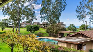 A pool area with a view of a building complex, surrounded by trees and greenery.