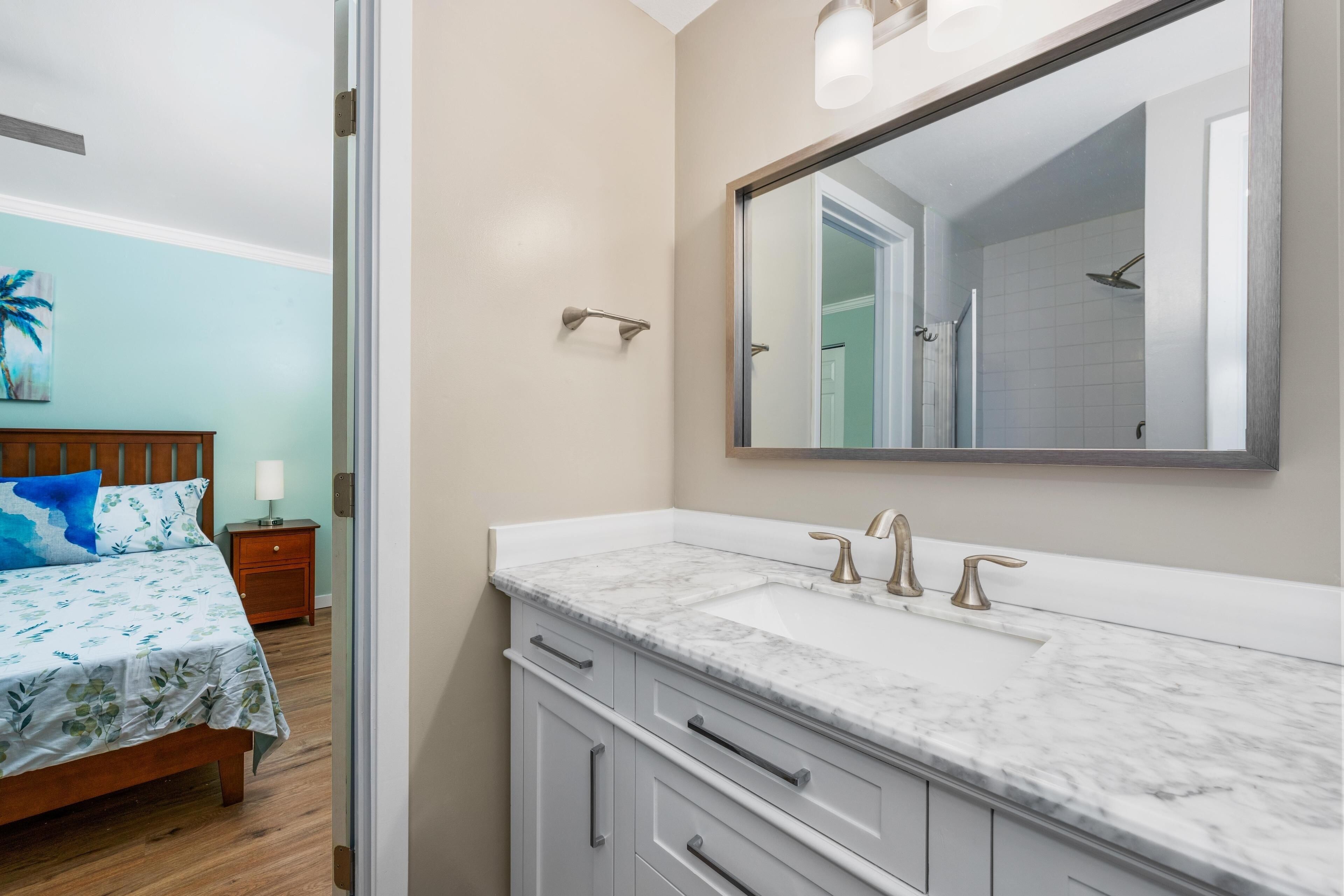Une salle de bain avec un grand miroir, un lavabo blanc et une douche.