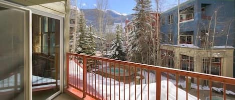 A balcony with a view of a snowy landscape, including trees and buildings.