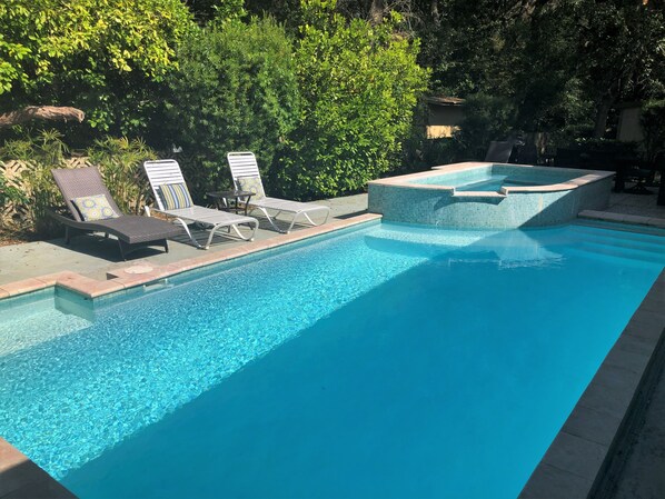Relax by the pool surrounded by lush greenery and enjoy a soak in the hot tub.