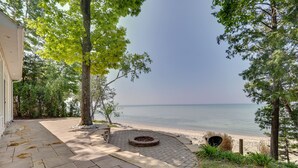 Eine gepflasterte Terrasse mit einem runden Feuerkorb, mit Blick auf einen Strand.