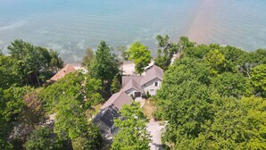 Ein Haus, umgeben von dichter Vegetation, mit freiem Blick auf ein Gewässer im Hintergrund.