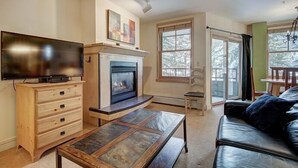 Un salon avec une cheminée, un téléviseur, un meuble en bois et un canapé en cuir.