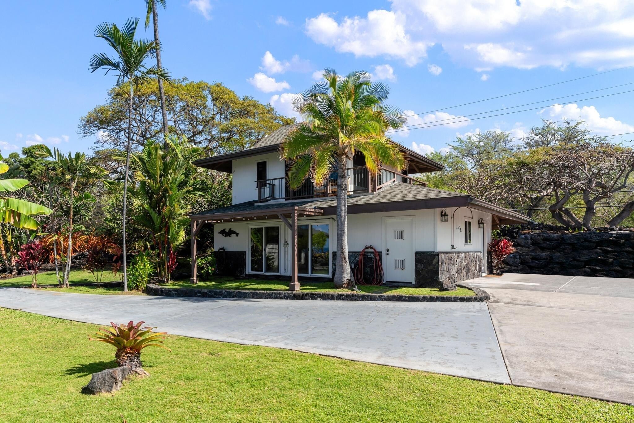 A two-story house with a covered porch, a stone wall, and a well-maintained lawn.