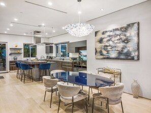 Una cocina moderna con una isla central, taburetes de bar y una mesa de comedor con sillas.