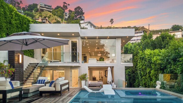 A modern two-story house with a swimming pool, outdoor seating, and a staircase leading to the upper level.