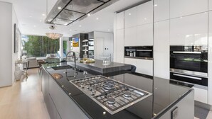 A modern kitchen with a central island, stainless steel appliances, and a view of the outdoors.