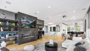 A modern living room with a fireplace, a dining area, and a kitchen.